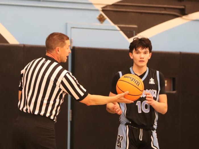 Official Dan Van Gorp of Redlands hands the ball to Ramona of Riverside's Sebastian Lopez.